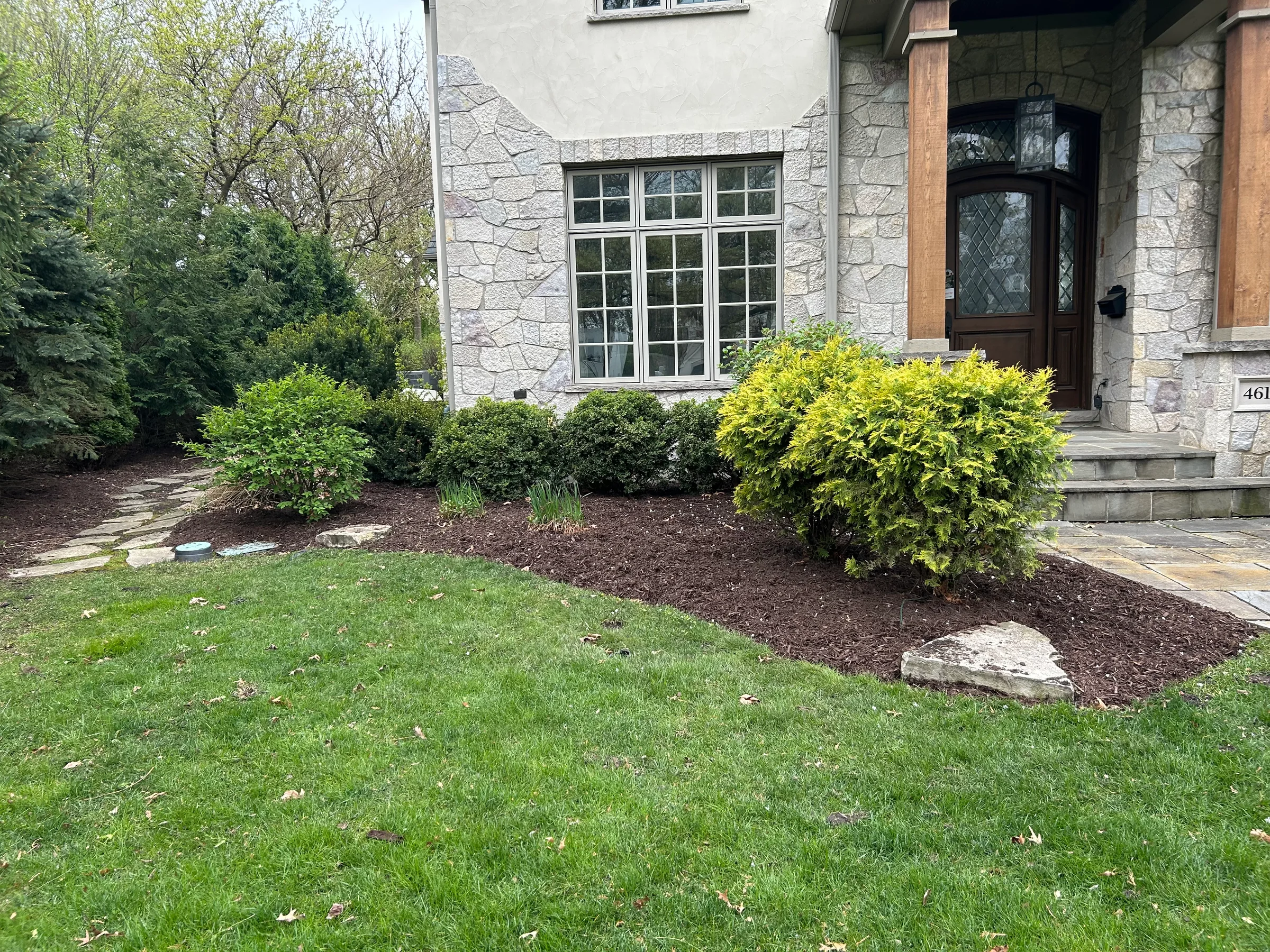 Defined mulch bed and shrubs beside a front entry